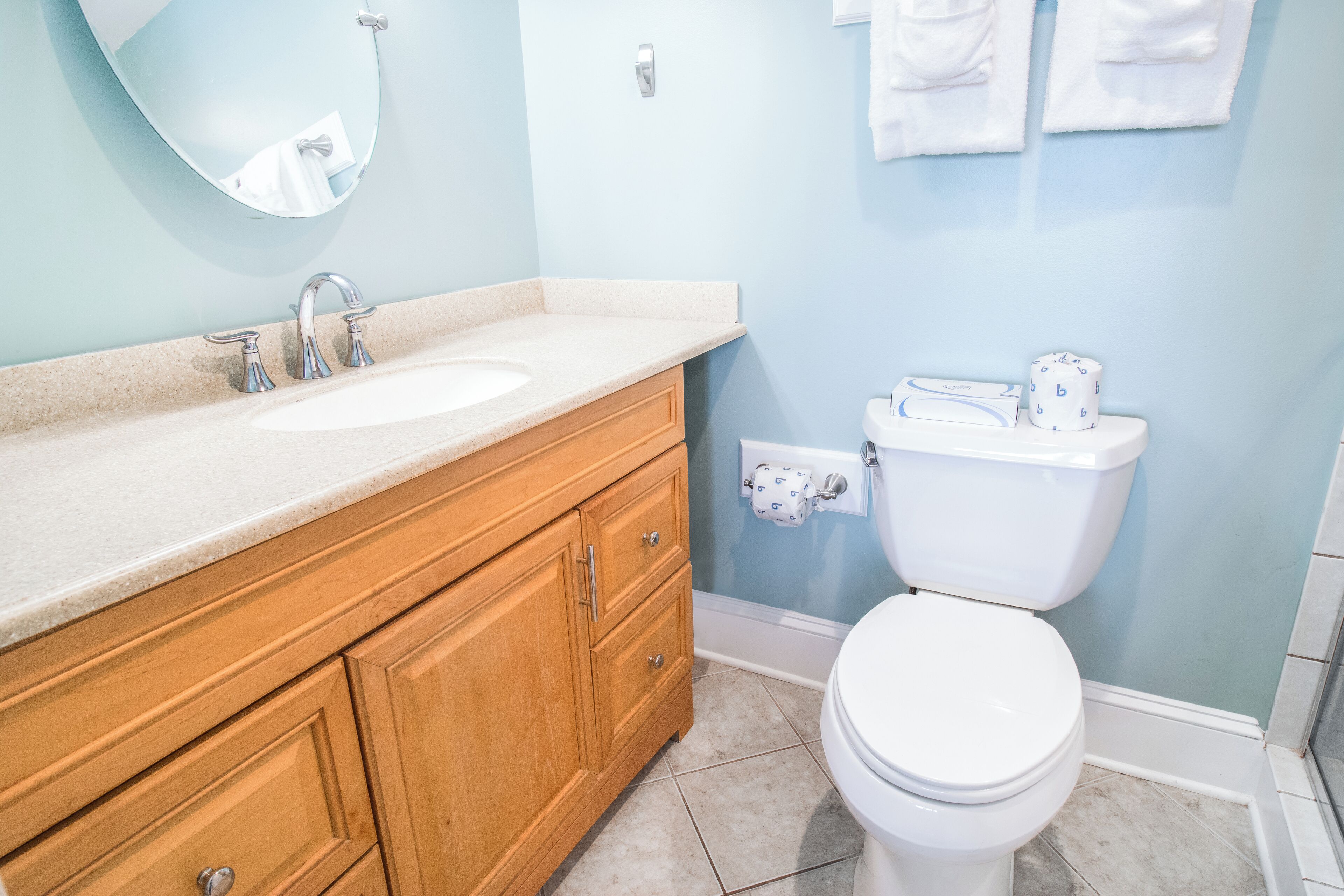 Une salle de bain avec un meuble-lavabo en bois, un lavabo blanc, des toilettes et un miroir.