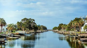 Un río tranquilo con barcos amarrados a sus orillas, rodeado de árboles y un puente a lo lejos.