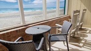 A balcony with wicker furniture, a view of the beach, and a brick wall. - The Oceanfront Litchfield Inn (Pawleys Island)