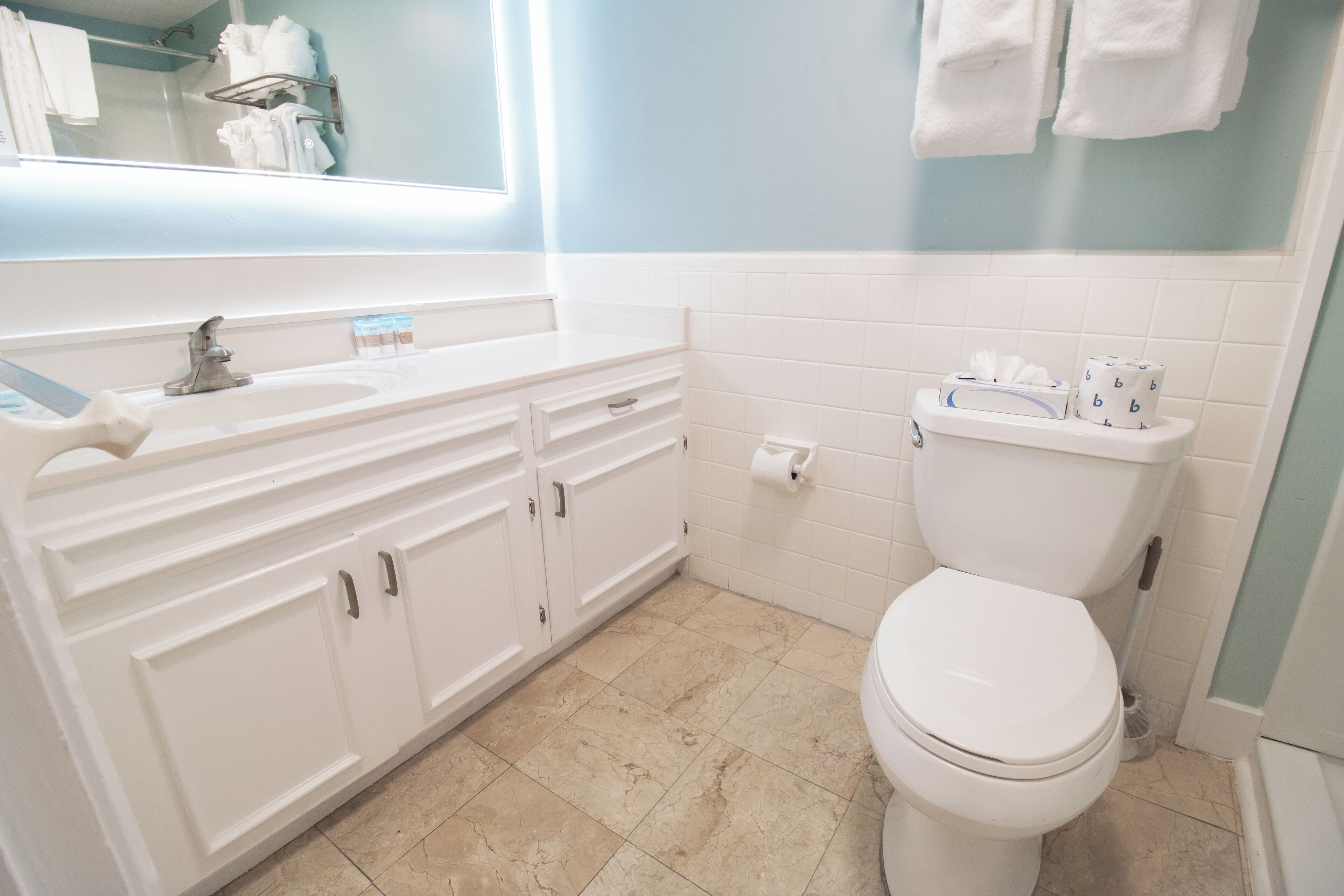 A bathroom with a white sink, vanity, and toilet.