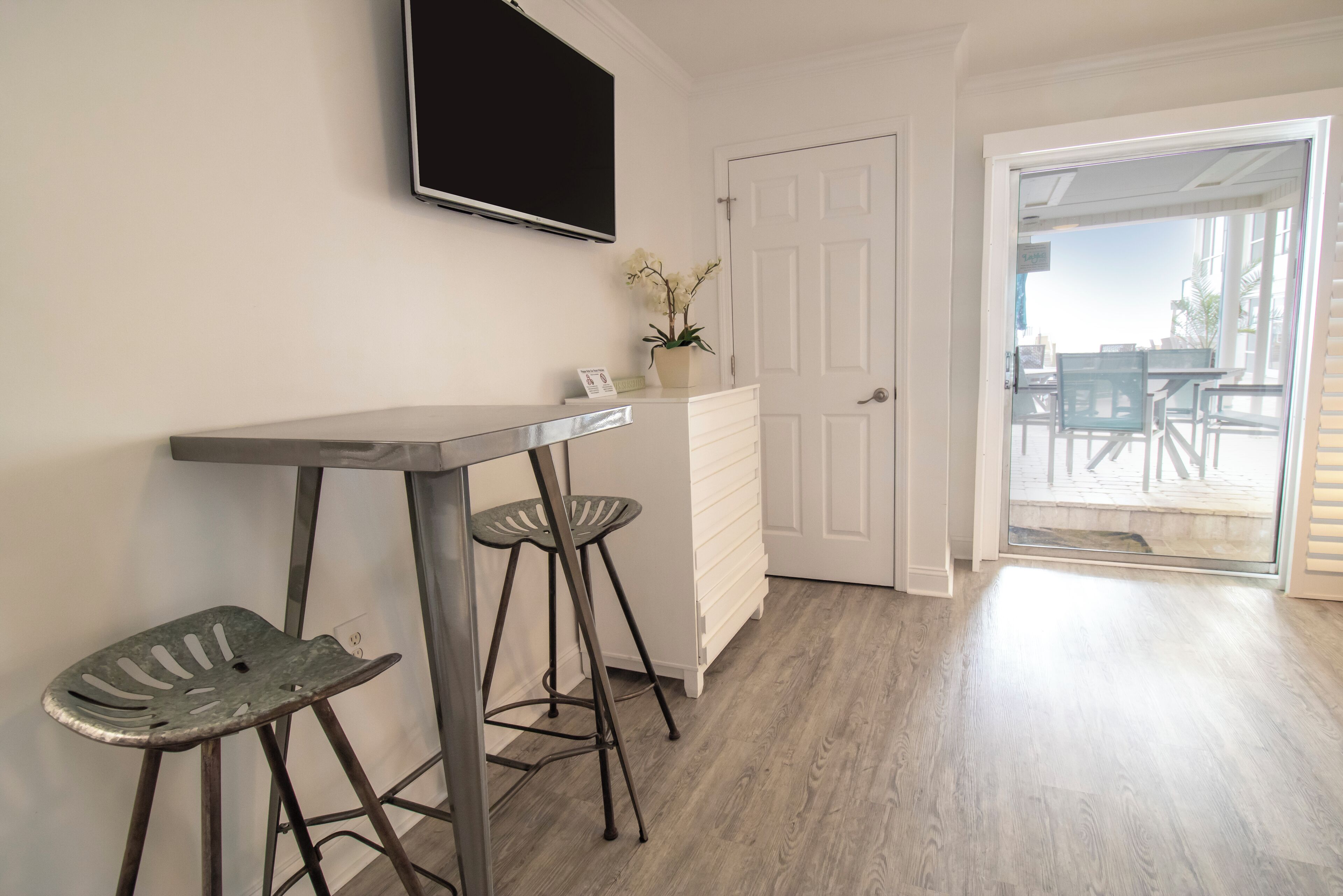 A kitchen with a bar stool, a small table, and a potted plant.