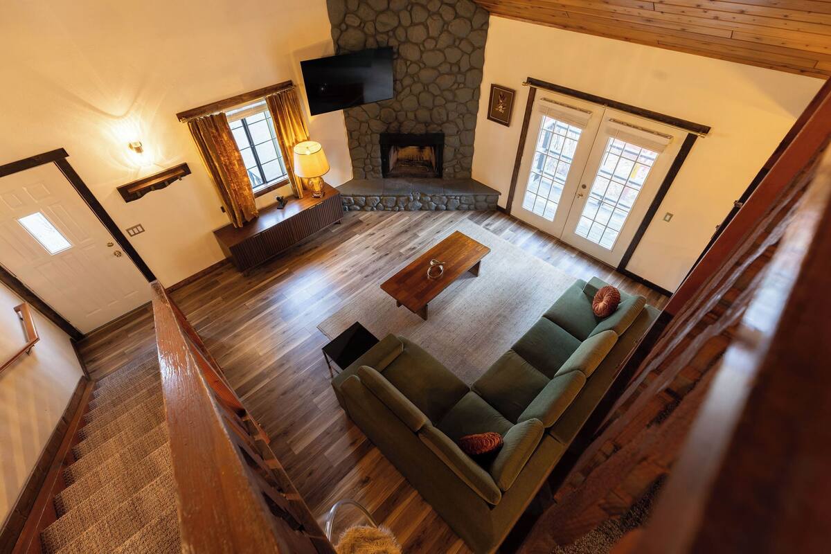 A living room with a stone fireplace, a green sofa, and a wooden coffee table.