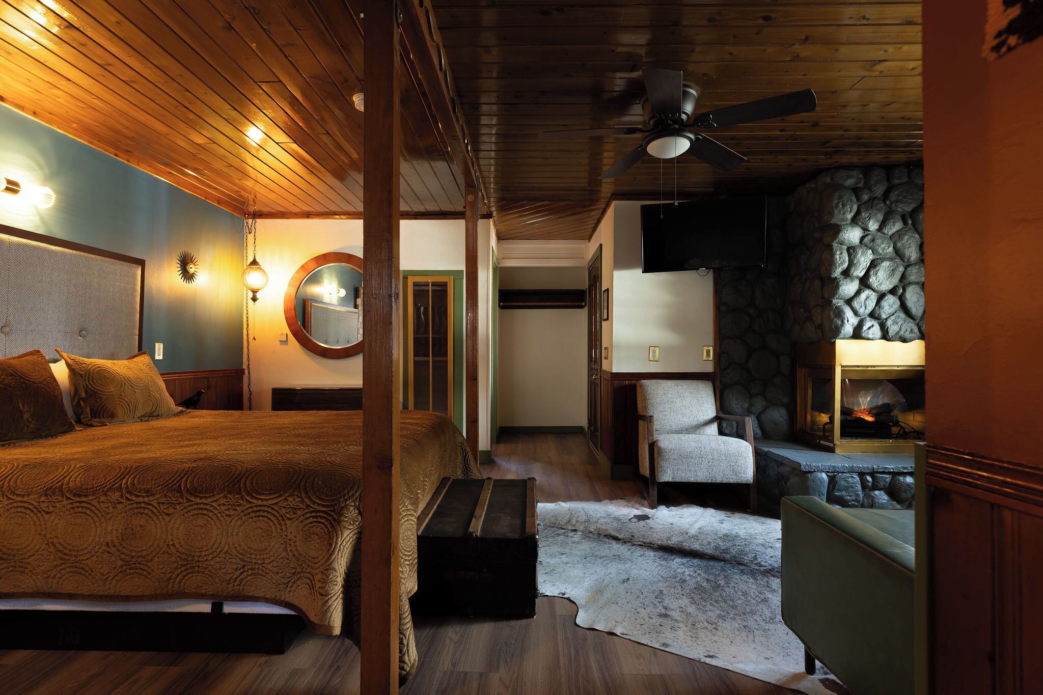 Ein gemütliches Schlafzimmer mit einem großen Bett, Holzboden, Steinwand und Kamin.
