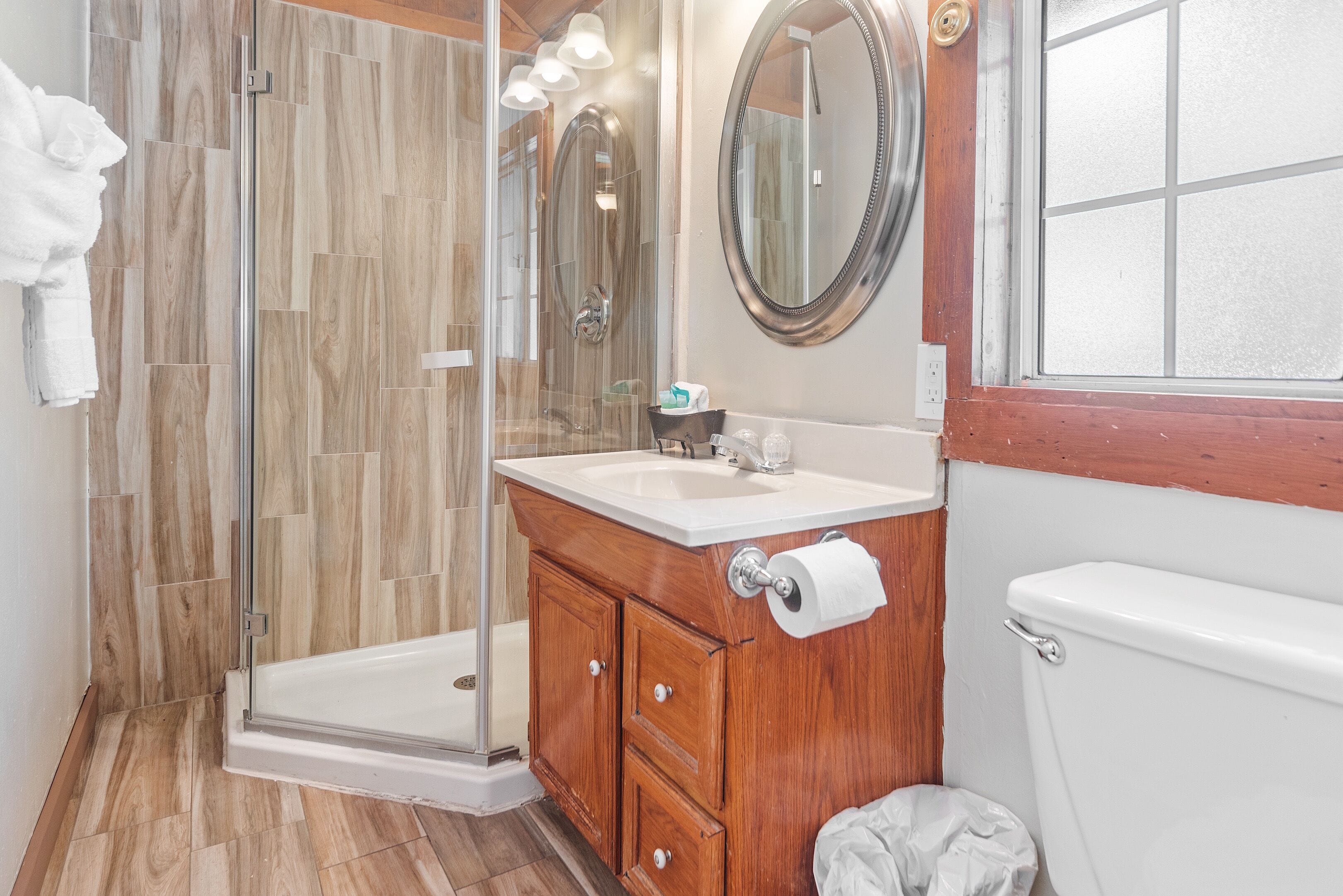 Une salle de bain avec une douche à parois de verre, un meuble-lavabo en bois et des toilettes.