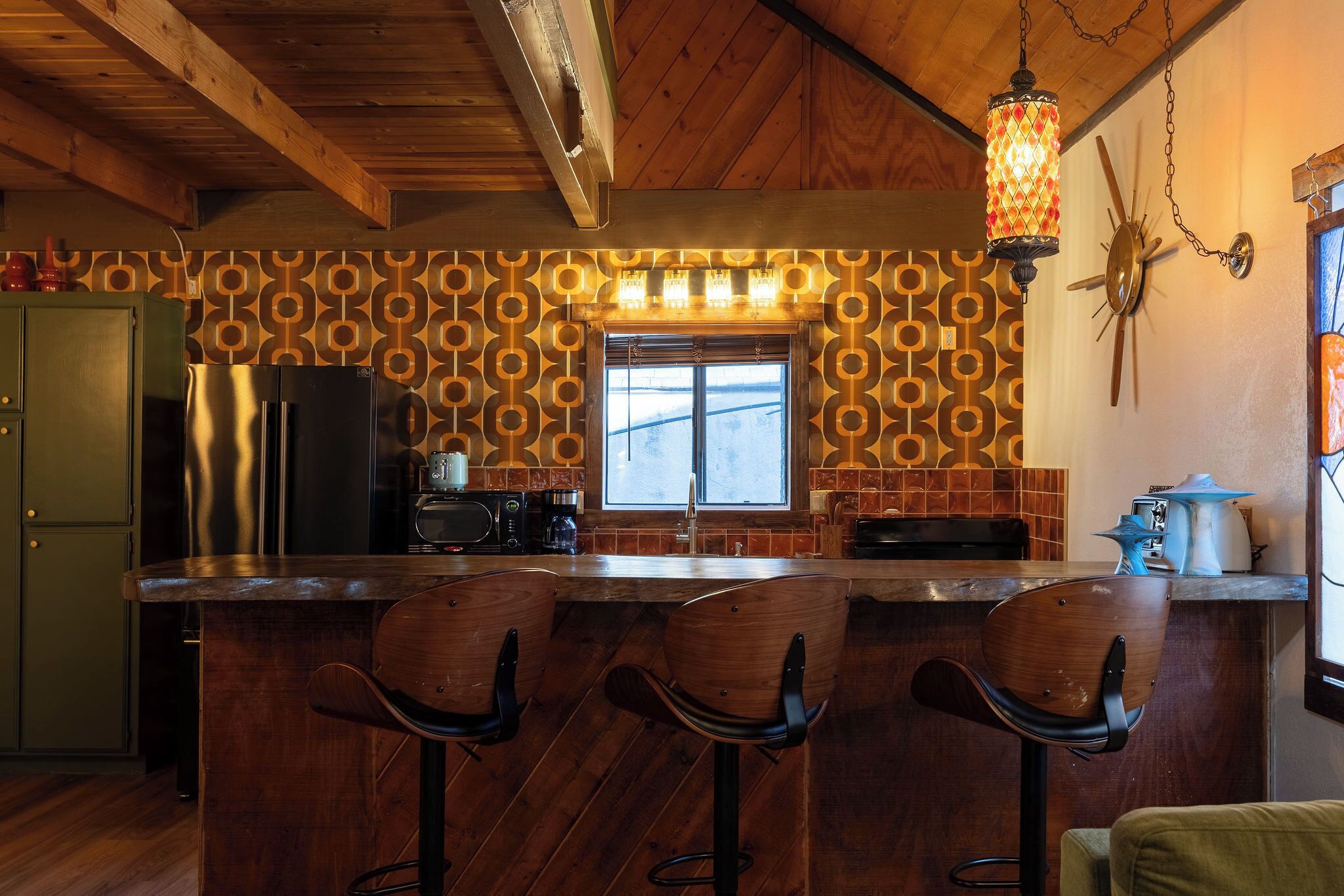 Uma cozinha com bancada de madeira, painel decorativo e janela com vista.