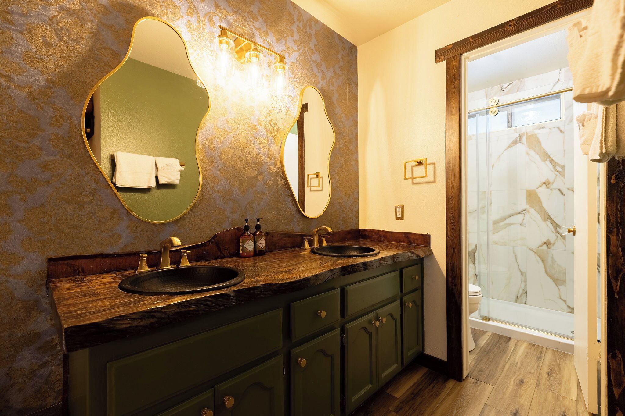 A bathroom with a wooden vanity, two sinks, and a glass shower enclosure.