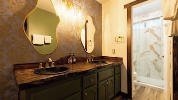 A bathroom with a wooden vanity, two sinks, and a glass shower enclosure.