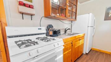 A kitchen with a white stove, wooden cabinets, and a white refrigerator.