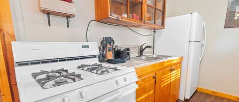 A kitchen with a white stove, wooden cabinets, and a white refrigerator.