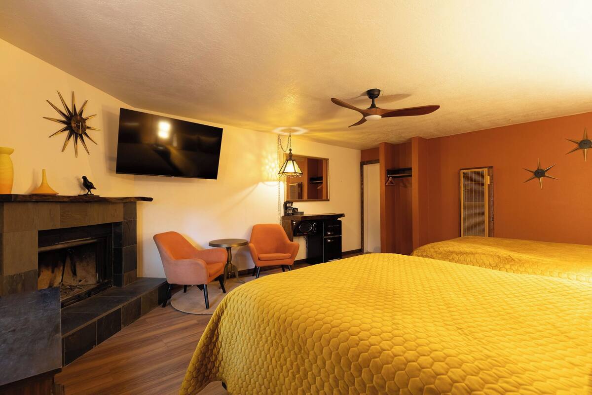 A hotel room with a large bed, a fireplace, a desk, and a television.