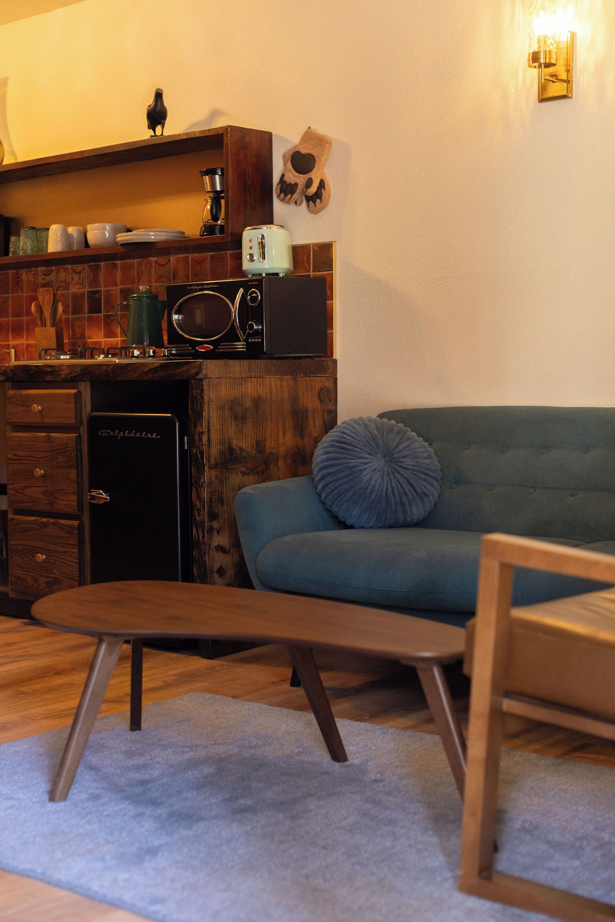 A compact living space with a kitchenette, a blue sofa, and a wooden coffee table.