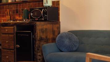 A compact living space with a kitchenette, a blue sofa, and a wooden coffee table.