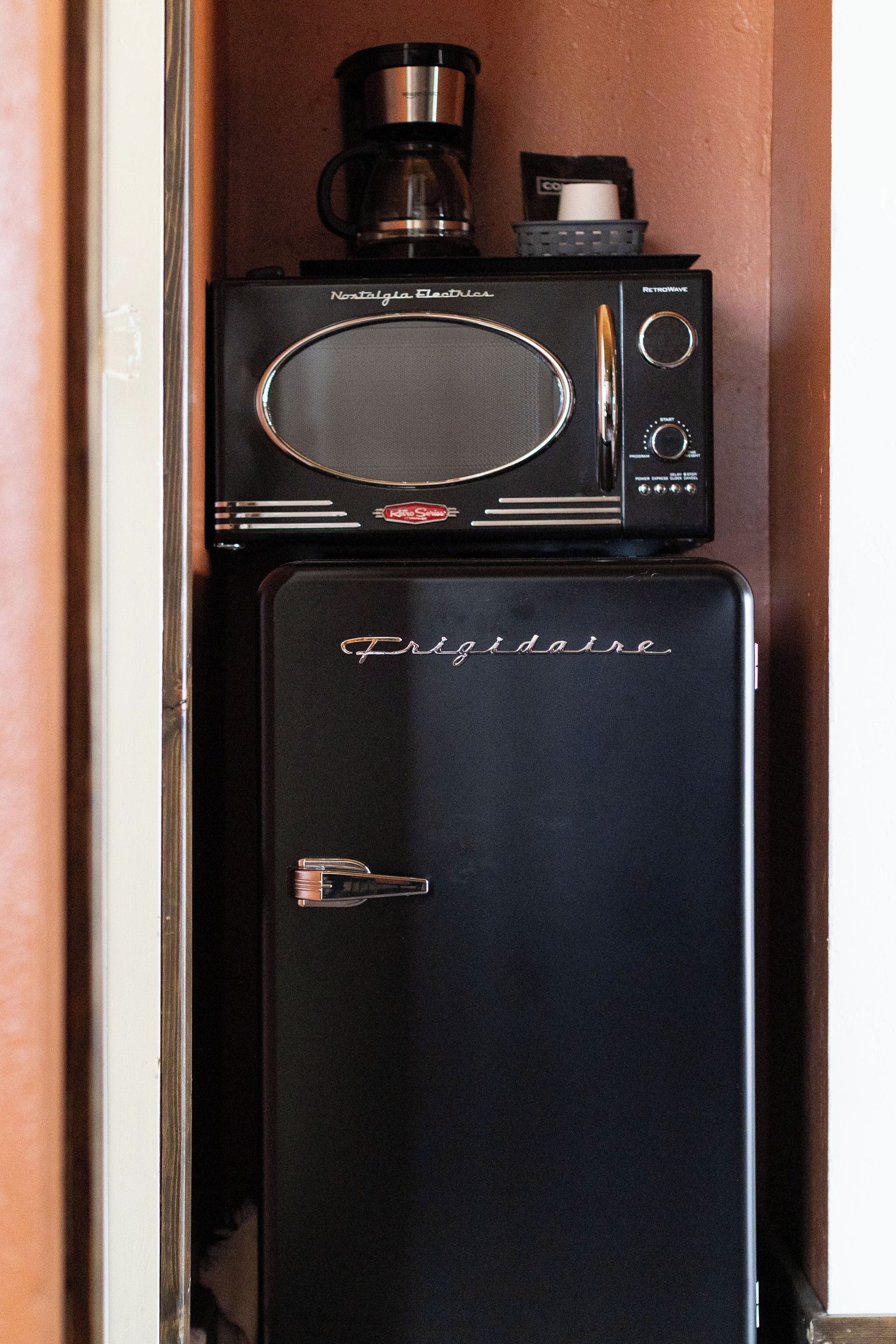 Ein alter Kühlschrank mit einer Kaffeemaschine darauf.