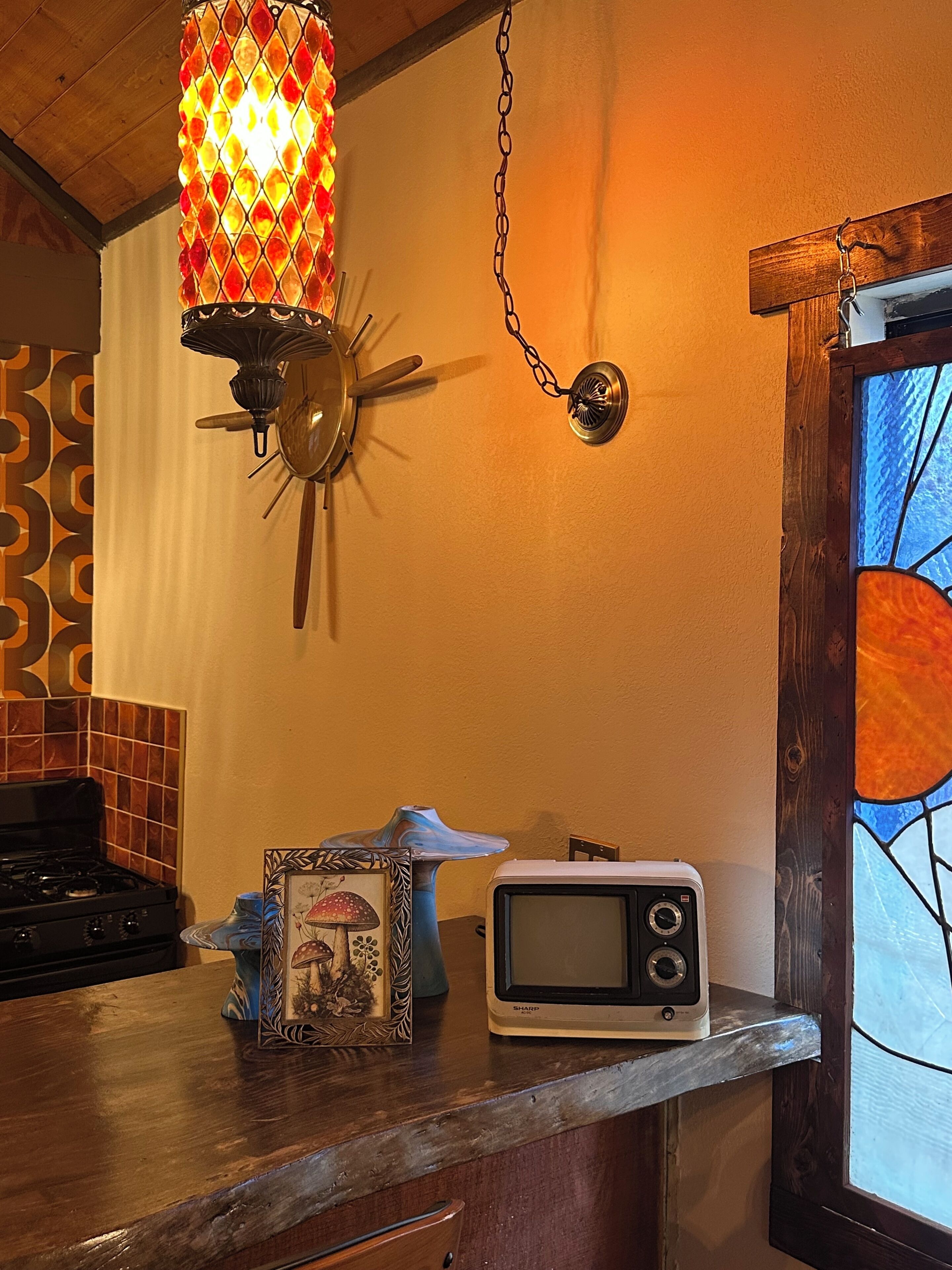 A kitchen with a stove, a microwave, a decorative lamp, and a framed picture on the counter.
