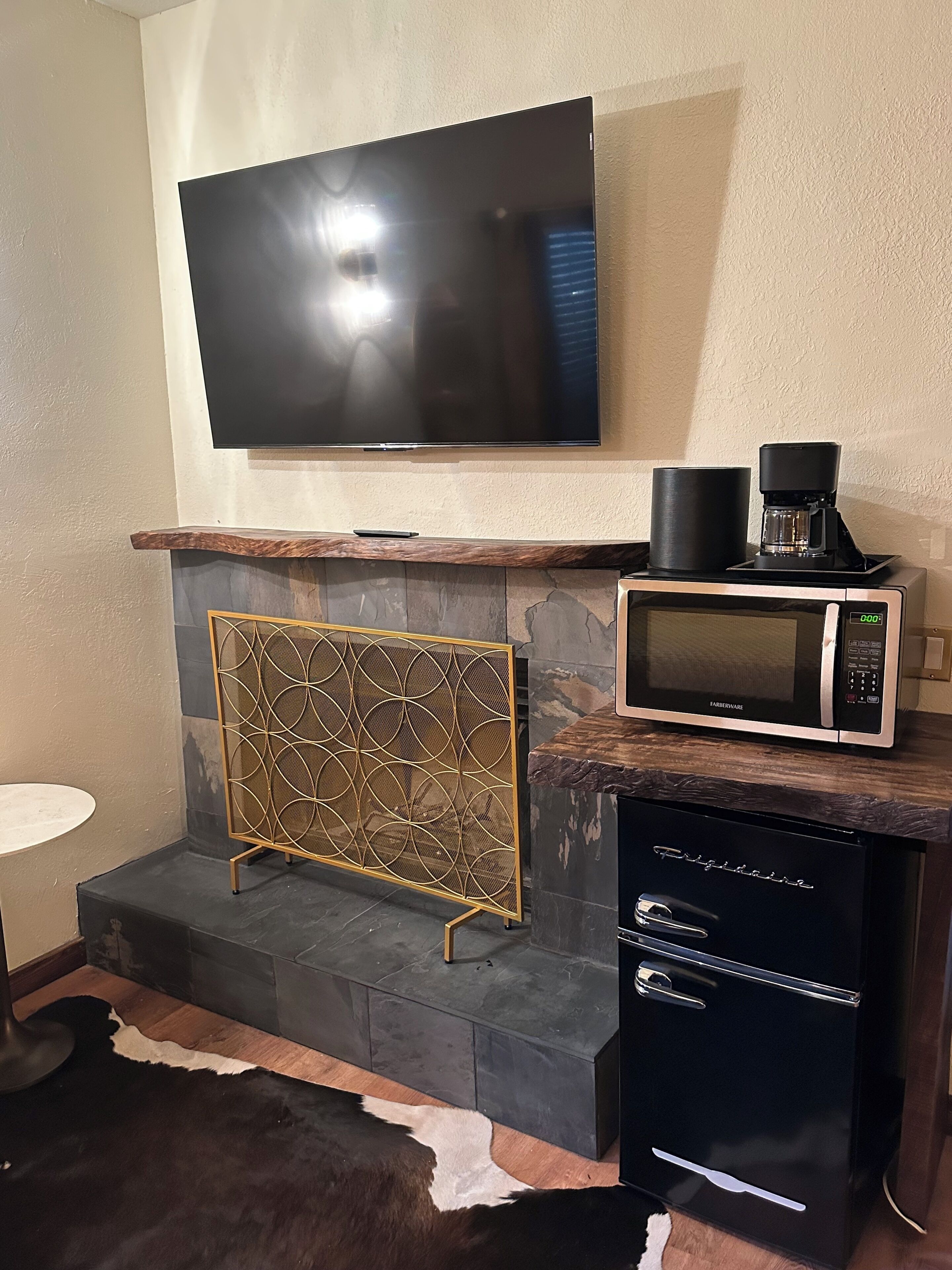 Eine moderne Küche mit Flachbildfernseher über einem Steinkamin, einer Kaffeemaschine, einer Mikrowelle und einem Kühlschrank.
