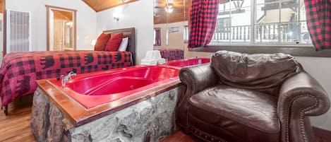 A room with a stone bathtub, a leather armchair, and a bed with a checkered blanket.