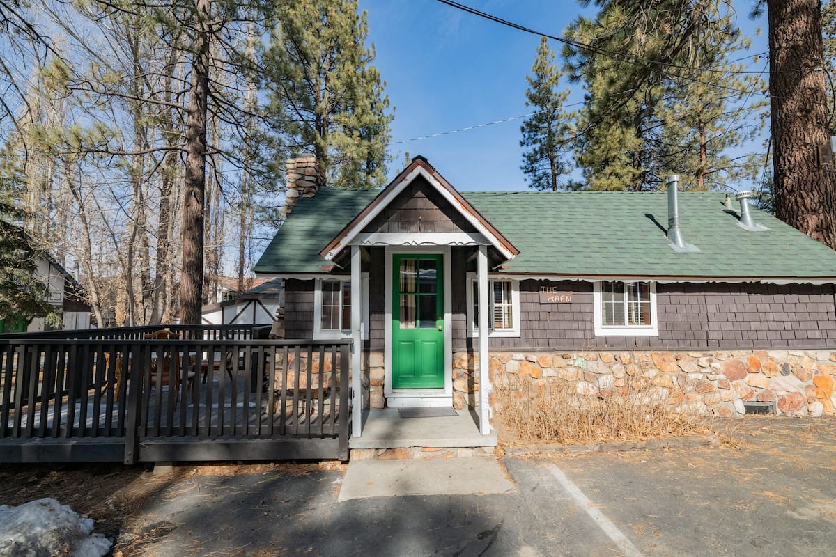 A small stone house with a green door, a porch, and a chimney.