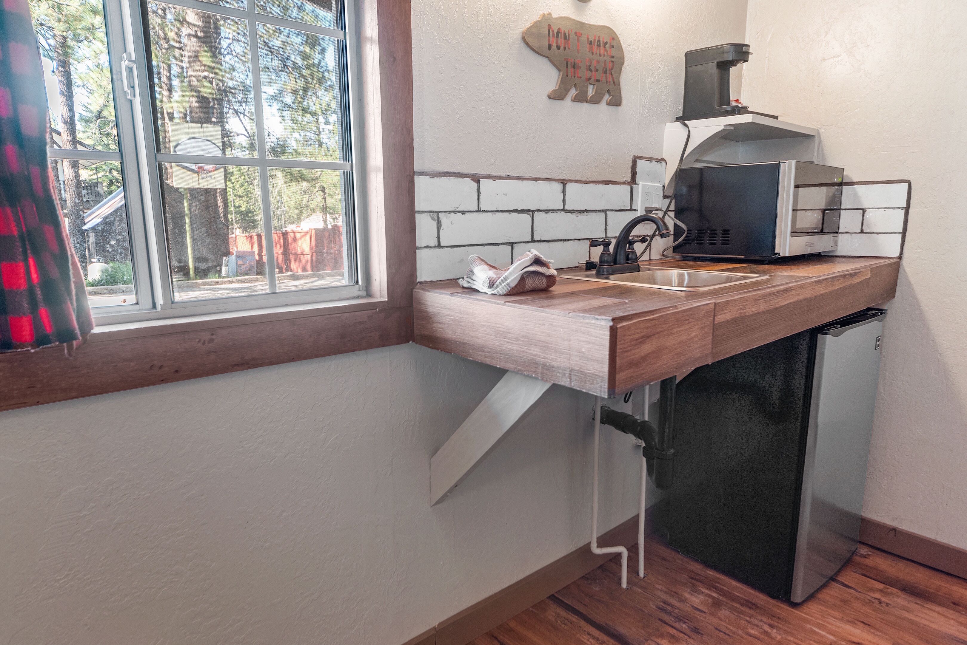A kitchen with a wooden countertop, a sink, a coffee maker, and a refrigerator.
