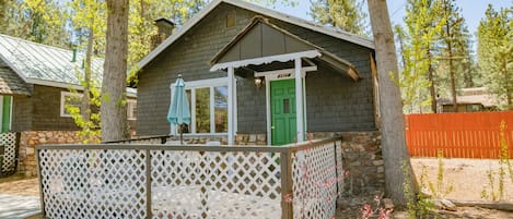 A small cabin with a stone foundation, a green door, and a white lattice fence.