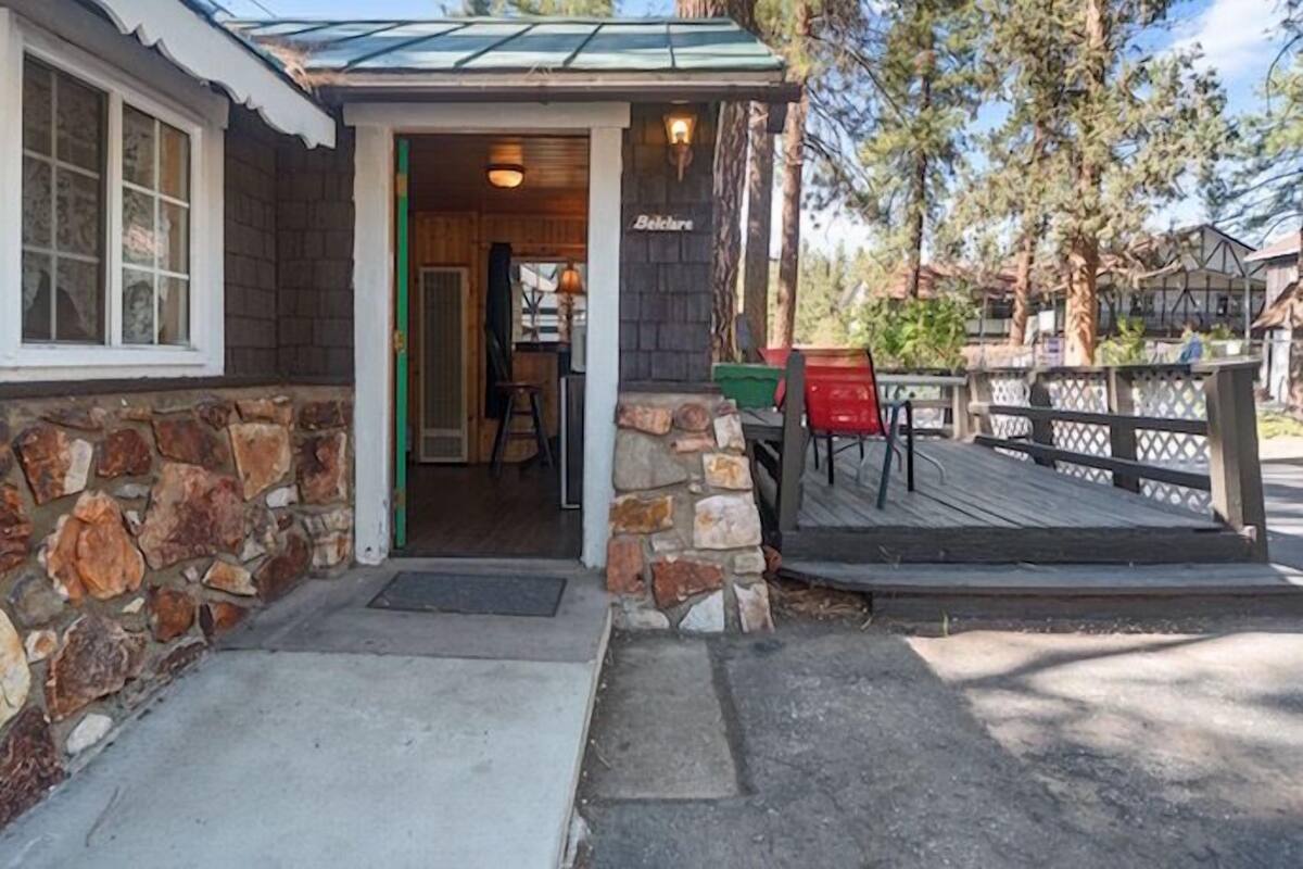 A rustic building with a stone facade, a wooden deck, and a green door.
