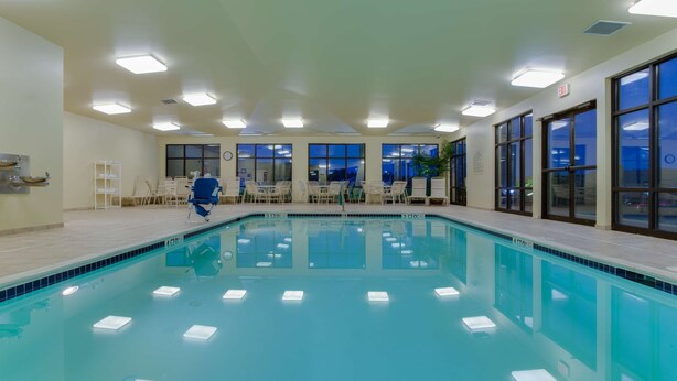 Una piscina interior con agua cristalina, rodeada de sillones de descanso y una zona de estar.