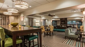 Un amplio vestíbulo de hotel con comedor, espacios de descanso y kitchenette.