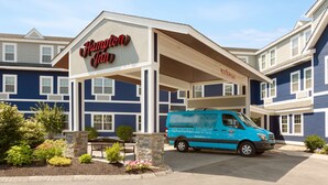 A Hampton Inn hotel with a blue exterior, a van in front, and a welcoming sign. - Hampton Inn Dover (Dover)