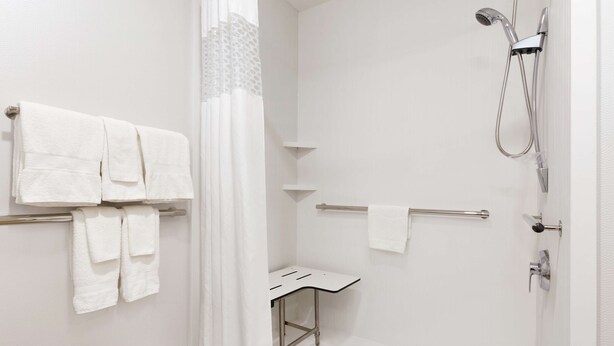 A modern bathroom with a shower, a towel rack, and a small table.