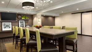 A modern dining area with a rectangular table, multiple chairs, and a chandelier. - Hampton Inn Dover (Dover)