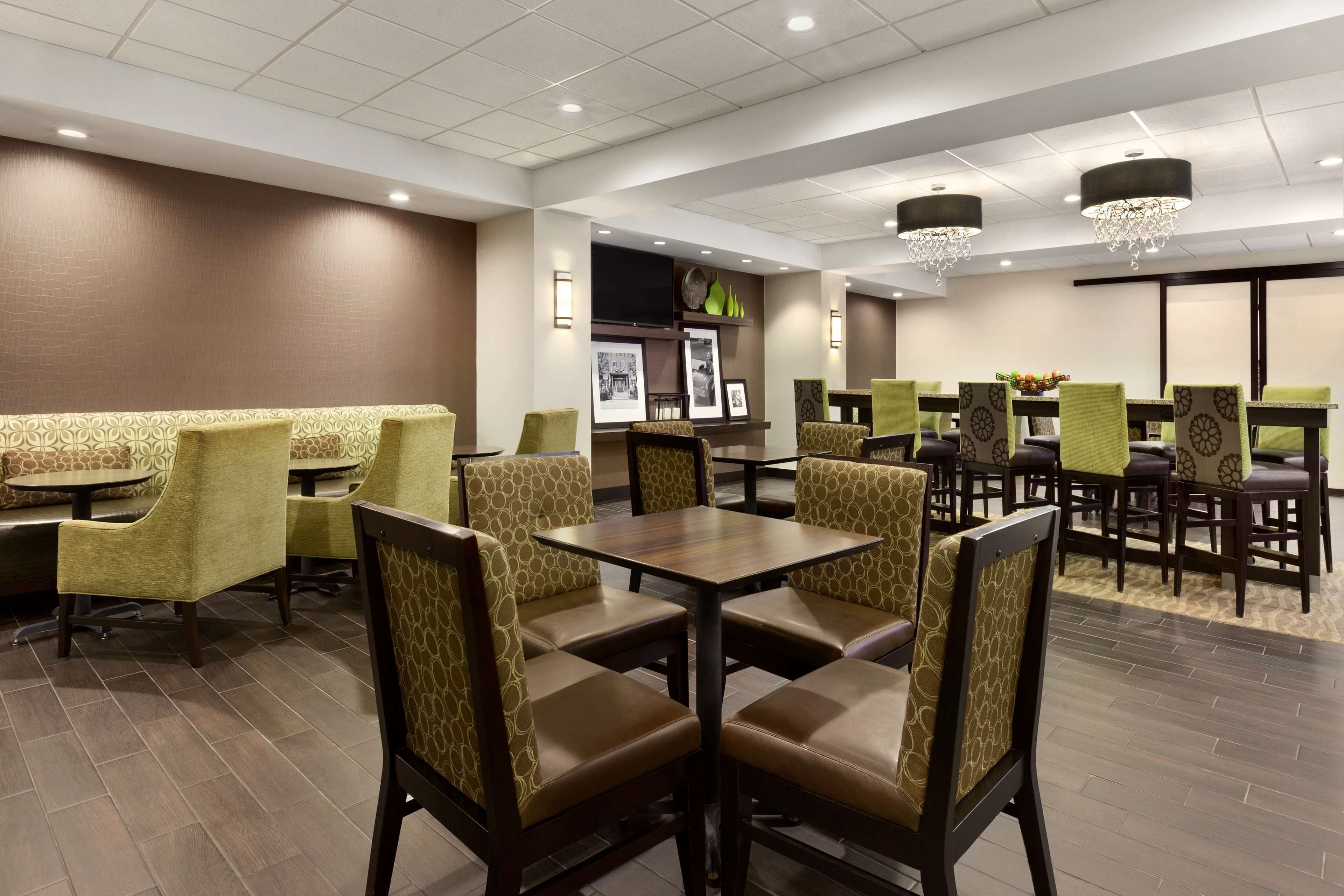Een restaurantgedeelte in een hotel, met zitbanken en tafels, versierde stoelen en een kroonluchter.