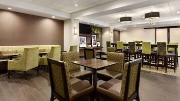 Een restaurantgedeelte in een hotel, met zitbanken en tafels, versierde stoelen en een kroonluchter.