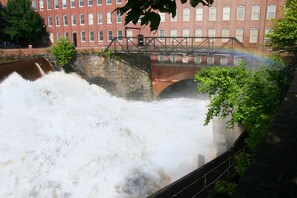 A large waterfall with a bridge and a red brick building in the background.