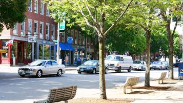 A street with benches, cars, and buildings including a restaurant and a bar/lounge.