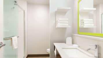 A modern bathroom with a glass shower enclosure, a white sink with a chrome faucet, and a mirror with a green frame.