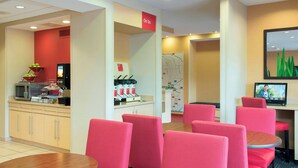 Um saguão de hotel com assentos vermelhos, um espaço para café e um mapa na parede.