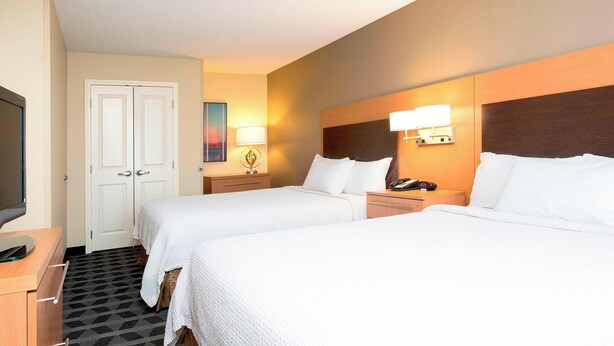 Quarto de hotel com duas camas, televisão, escrivaninha e porta.