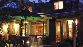 A modern house with a patio area featuring outdoor furniture and a green umbrella.