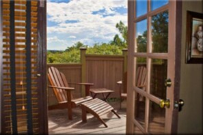 A wooden deck with two chairs and a table, a wooden fence, and a view of greenery. - Lodge At Sedona (Sedona)