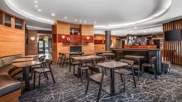 Een modern restaurant met een gebogen plafond, houten accenten en een kamerbreed tapijt met dessin.
