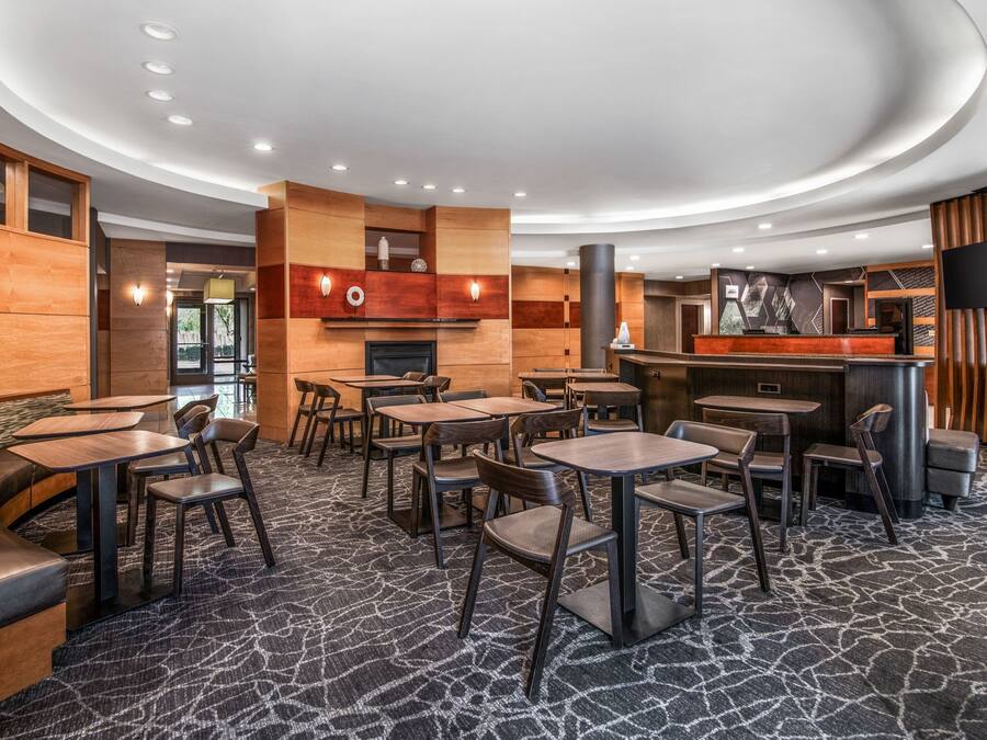 Een modern restaurant met een gebogen plafond, houten accenten en een kamerbreed tapijt met dessin.