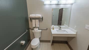 A bathroom with a toilet, a towel rack, a sink, and a mirror.