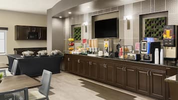 A modern breakfast bar with a flat-screen TV, a coffee machine, and a juice dispenser.