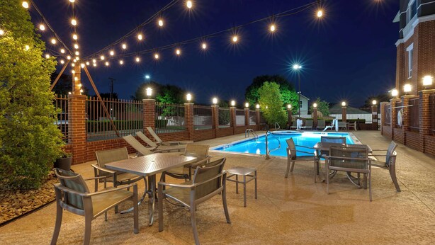 An outdoor pool area with string lights, a pool, and patio furniture. - Best Western Plus Duncanville/Dallas (Duncanville)