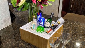 A wooden ice bucket filled with various bottles and glasses on a granite countertop. - Best Western Plus Duncanville/Dallas (Duncanville)
