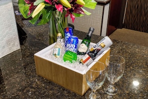 A wooden ice bucket filled with various bottles and glasses on a granite countertop. - Best Western Plus Duncanville/Dallas (Duncanville)