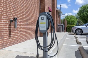 An electric vehicle charging station mounted on a brick wall. - Best Western Plus Duncanville/Dallas (Duncanville)