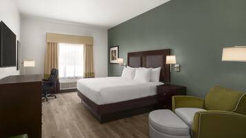 A hotel room with a bed, a desk, a chair, and a sofa.