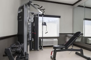 A gym with exercise equipment, a bench, and a large window.