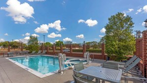 A swimming pool with lounge chairs and a table, surrounded by a brick wall and greenery. - Best Western Plus Duncanville/Dallas (Duncanville)