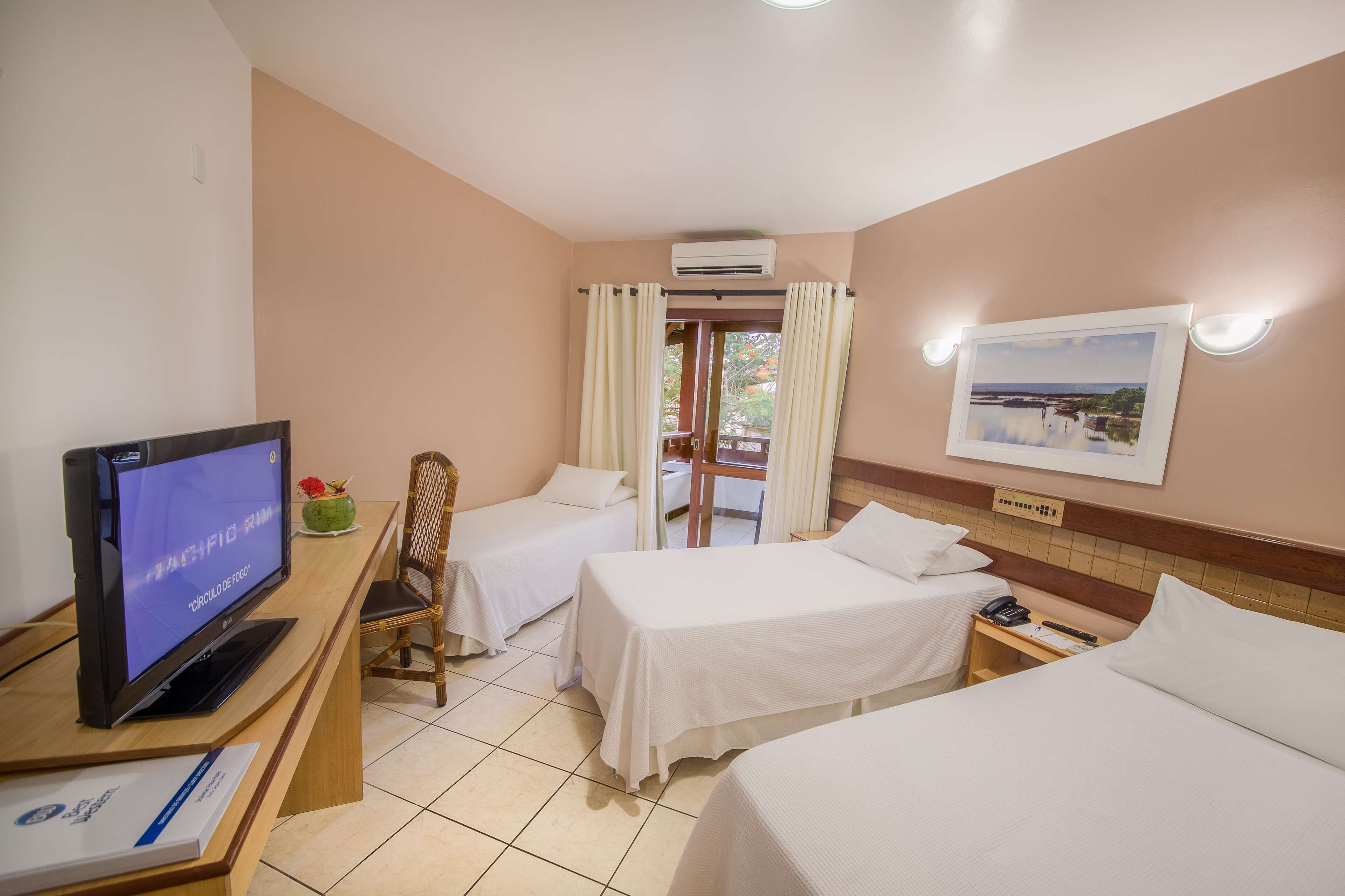 Une chambre d’hôtel avec deux lits, un bureau avec un ordinateur, une chaise, une petite table avec un téléphone et une fenêtre avec des rideaux.